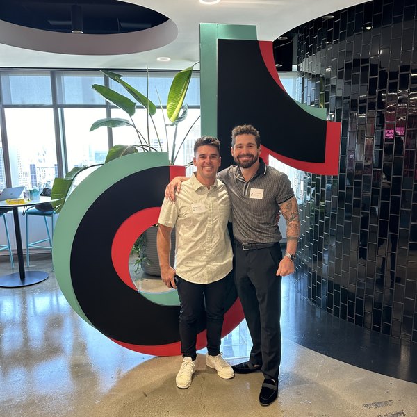 Micah Whitehead and Riley Cronin, co-founders of zeroto1, in front of the TikTok mark